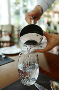 Close-up of water being poured into a glass in a restaurant setting.