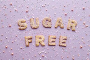 Flatlay of sugar-free cookie letters with sprinkles on a pink background.