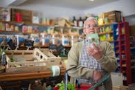 Elderly man examines product in grocery store aisle, representing daily shopping routine.