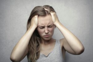 Young woman expressing stress and frustration while holding her head.